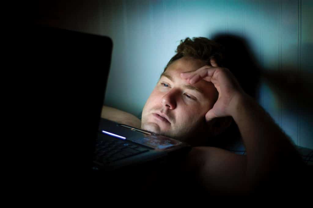 Man facing laptop, lacking good night's sleep